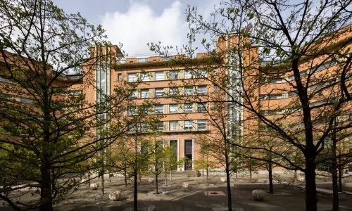 Backsteingebäude des Campus UFR3S, gesehen von einem mit jungen Bäumen bepflanzten Hof