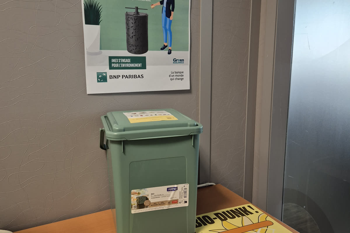 Bioseau vert pos&eacute; sous une affiche de sensibilisation au tri des biod&eacute;chets